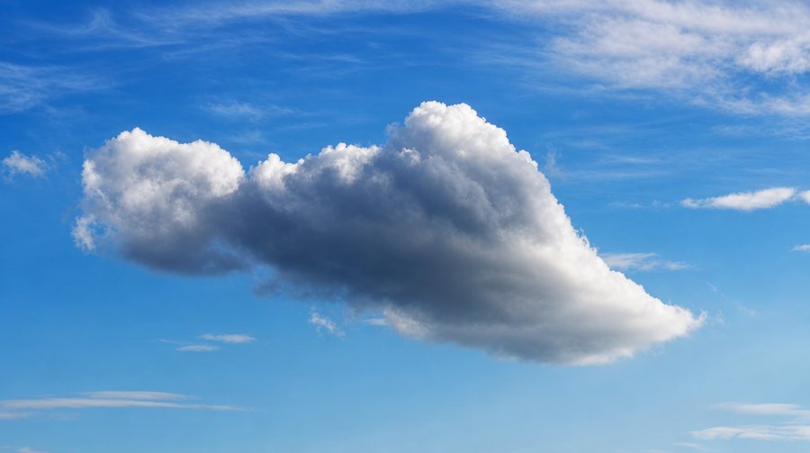Eine große weiße Wolke vor tiefblauem Himmel.